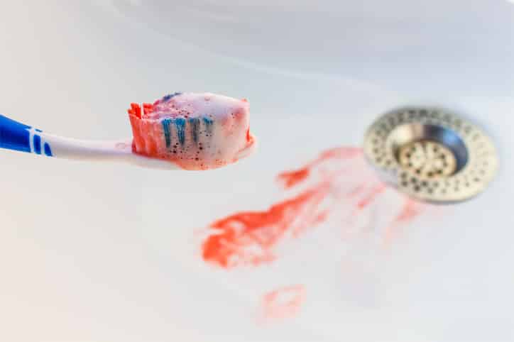 Blood on the toothbrush on background of sink.