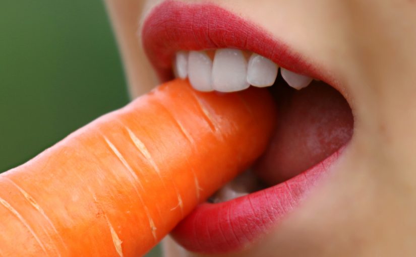 Woman eating carrot with sensitive teeth
